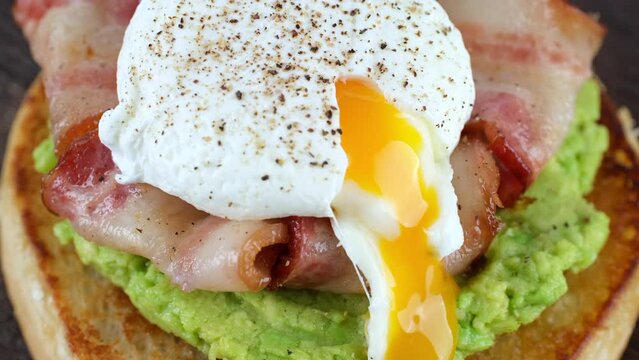 Chef hands cutting poached egg on bacon and avocado mashed toast