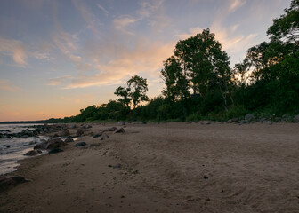 rocky sea shore before sunrise, dark stone silhouettes and colorful sky