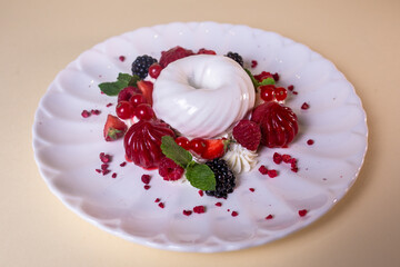 White cream cake with fresh berries on white plate. Isolated on beige background