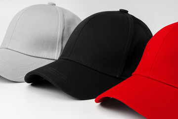 Lineup of Four Blank Baseball Caps in Red, White, and Black on a White Background