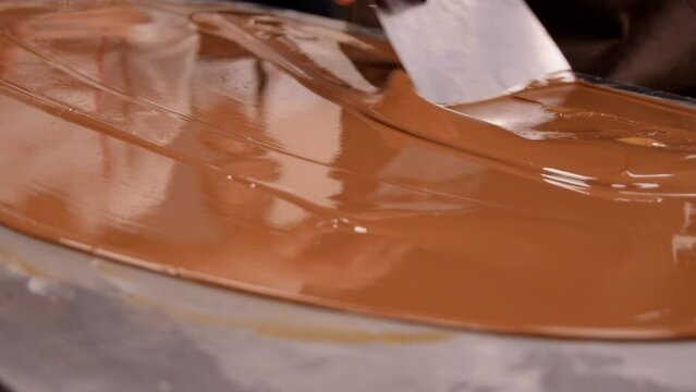 Chef tempering chocolate on a metal table at a master class. Close up