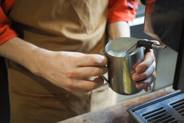 Fototapeta na wymiar preparing fresh coffee, holding pitcher for steaming milk. Preparation and service concept