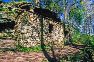 Old stone house by a rock in the woodland at spring