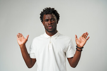 Young Man Expressing Confusion and Surprise With Hands Up Against a Neutral Background