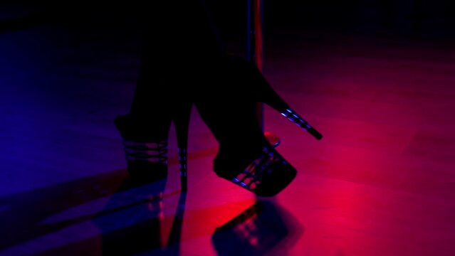 Slender legs of pole dancer in high heels, close-up. Close-up of stripper shoes in the club. Pole dance. 