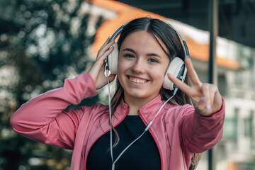 student girl at the institute wearing headphones and making ok gesture