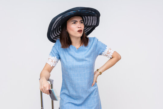 Asian woman in summer attire looking perplexed and confused, standing with suitcase isolated on white