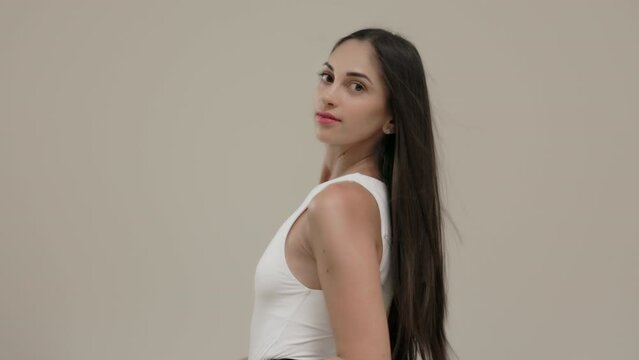 A brunette girl with long straight hair poses in the studio against a light background.