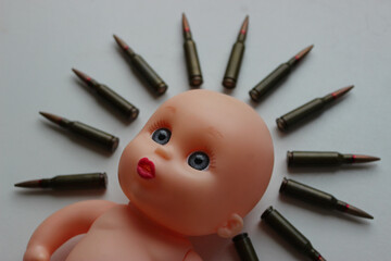 Victims of war concept image. Live ammunition is placed around the doll's head with sad eyes
