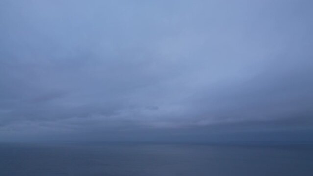 Timelapse moody dark rainy Nimbostratus clouds slowly moving over sea. Abstract aerial nature summer ocean sea and sky view. Weather and Climate Change