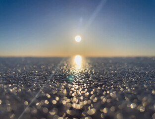 Defocus natural background. Sunset on the background of a frozen lake. Bokeh. Defocus lights. Ice. Winter. The sun's rays.
