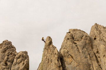 A person is standing on a rock face, looking down at the ground. Concept of adventure and excitement, as the person is taking on a challenging climb