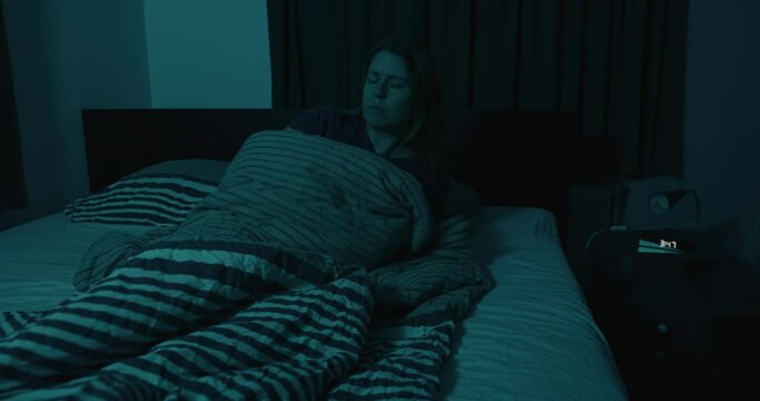 Dolly of woman suddenly waking up from nightmare and turning on nightlight