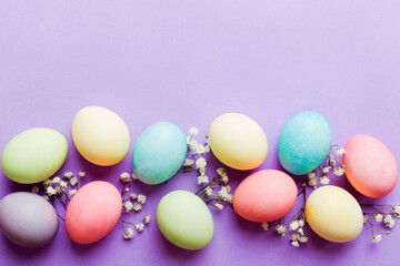 Happy Easter composition. Easter eggs on colored table with gypsophila. Natural dyed colorful eggs background top view with copy space