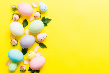 Happy Easter. Easter eggs on colored table with yellow roses. Natural dyed colorful eggs background top view with copy space