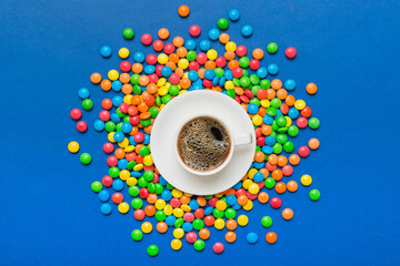 Coffee cup with chocolates and colored candy. Top view on table background with copy space