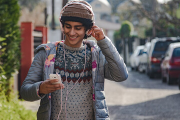 young latin hispanic man with headphones and phone on the street
