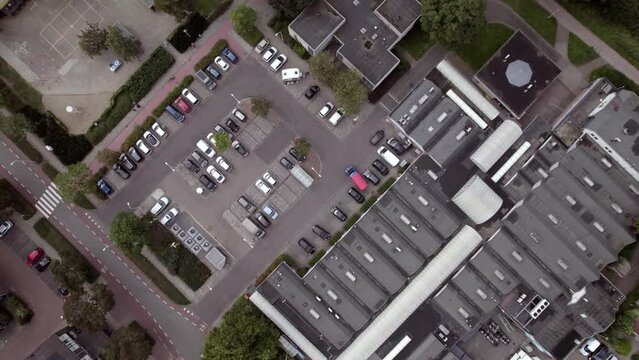 Ascending aerial movement revealing shopping mal car parking lot in Dutch residential neighborhood. Infrastructure transportation asphalt. Car park