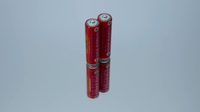 DOMODEDOVO, RUSSIA, - AUGUST, 2023: Japanese red color round salt batteries Sony Superred size format AA, standart R6 on a glass surface. Closeup. Macro. Shot in motion