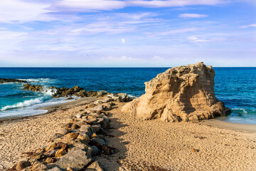 beautiful landscape of white sand beach with amazing waves during scenic sunrise or sunset with beautiful rock cliff , sea surf and nice cloudy sunset sky