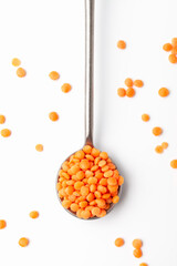 Dry red lentils in iron spoon on white background