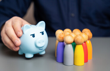 A businessman holds a blue piggy bank next to a group of people figures. Raise budget funds. Good...