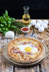 Rustic wooden table with homemade rye flour pizza and the ingredients from which it is made from the back.