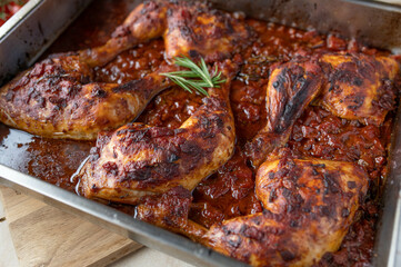 Braised chicken legs with italian red wine tomato sauce in a roasting pan