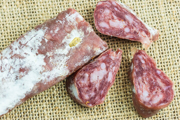 Slices of saucisson or salami on a burlap background