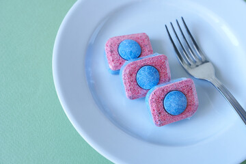 Dishwasher detergent tablet and clean dishes, top view.