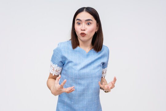 Upset Asian woman gesturing with hands, scolding someone, but momentarily distracted. isolated against a white background