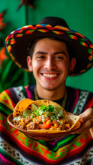 Mexican man smiling while holding a plate with mexican food over green background