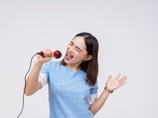 Enthusiastic Asian woman enjoying singing into a microphone, karaoke fun isolated on white