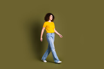 Fototapeta na wymiar Full length body photo of young beautiful funky woman strolling alone and poses casual apparel isolated on khaki color background