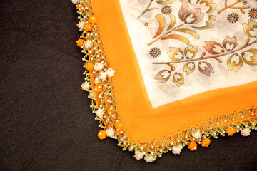 Hand-knitted scarf and headscarf samples, handmade embroidered and orange head scarf close-up.