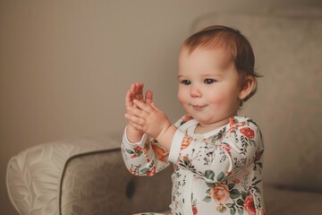 baby girl clapping hands in a floral onesie