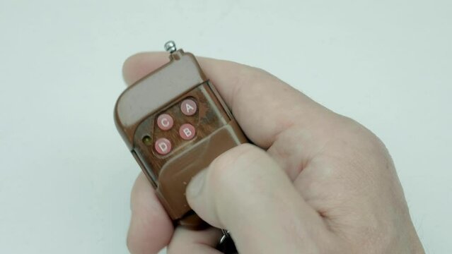 In a man's hand the alarm key fob, when the button is pressed, a red LED lights up, signaling that the protected object has been alarmed. Closeup. Macro