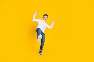 Fototapeta na wymiar Full length photo of positive cheerful boy wear white shirt waving arms hi empty space isolated yellow color background