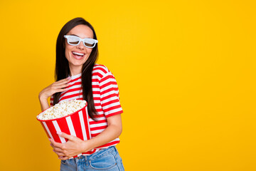 Portrait of positive overjoyed girl hold big pop corn bucket watch movie 3d glasses empty space...