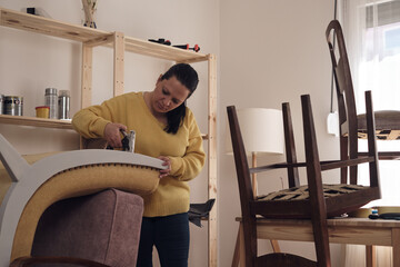 Woman working in a small home workshop for furniture repairing and restoration.