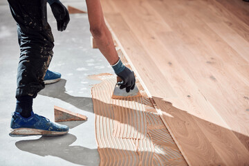 Professional handyman installing laminate flooring in a new apartment. - obrazy, fototapety, plakaty