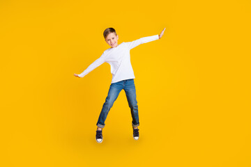 Fototapeta na wymiar Full length photo of excited good mood boy wear white shirt jumping high flying empty space isolated yellow color background