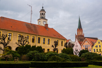 Town hall on old market square and Holy Mary gothic church in Trzebiatow, Poland - obrazy, fototapety, plakaty