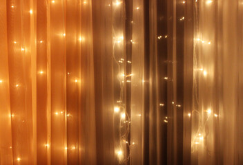Blurred Lights Of Garland With Small LED Lamps Behind Translucent Curtains
