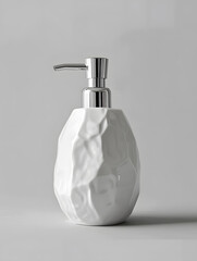 Fototapeta premium A liquid white soap dispenser made of glass bottle is placed on a white surface. The sleek, modern design adds a touch of fashion accessory to the space
