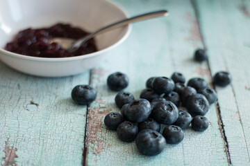 Blueberry pile next to blueberry jam in white bowl.