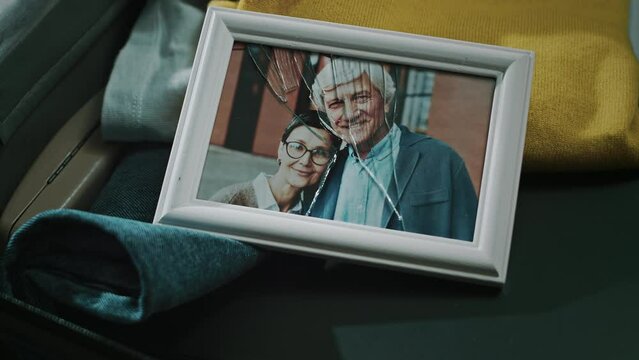 From above shot of broken picture frame of adult Caucasian married couple smiling at camera in suitcase