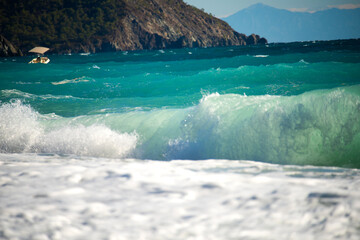 beautiful waves on a sunny day on an emerald beach and mountain coast. Mediterranean Sea.
