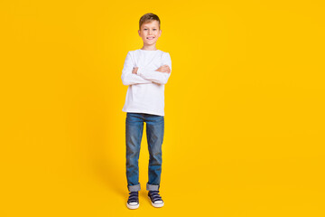 Full length photo of positive funky kid dressed white shirt arms folded isolated yellow color...