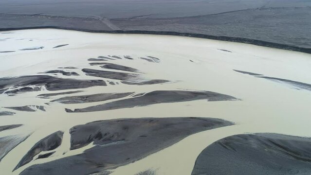Slow backward drone flight over a braiding glacial river on the vast glacial outwash plain Skei&eth;ar&aacute;rsandur in front of the terminus of the Vatnaj&ouml;kull glacier